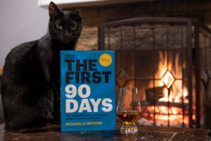 Book First 90 Days on a Table by a fire with a whiskey and a cat